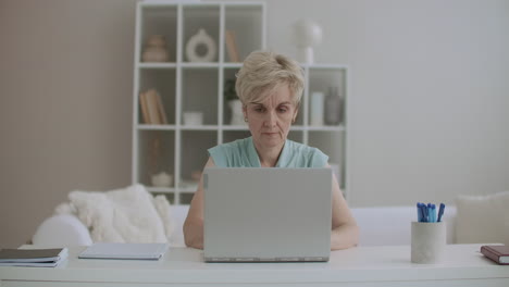 Eine-Frau-Mittleren-Alters-Arbeitet-Zu-Hause-Mit-Einem-Laptop,-Durchsucht-Internetseiten-Und-Kommuniziert-In-Sozialen-Netzwerken